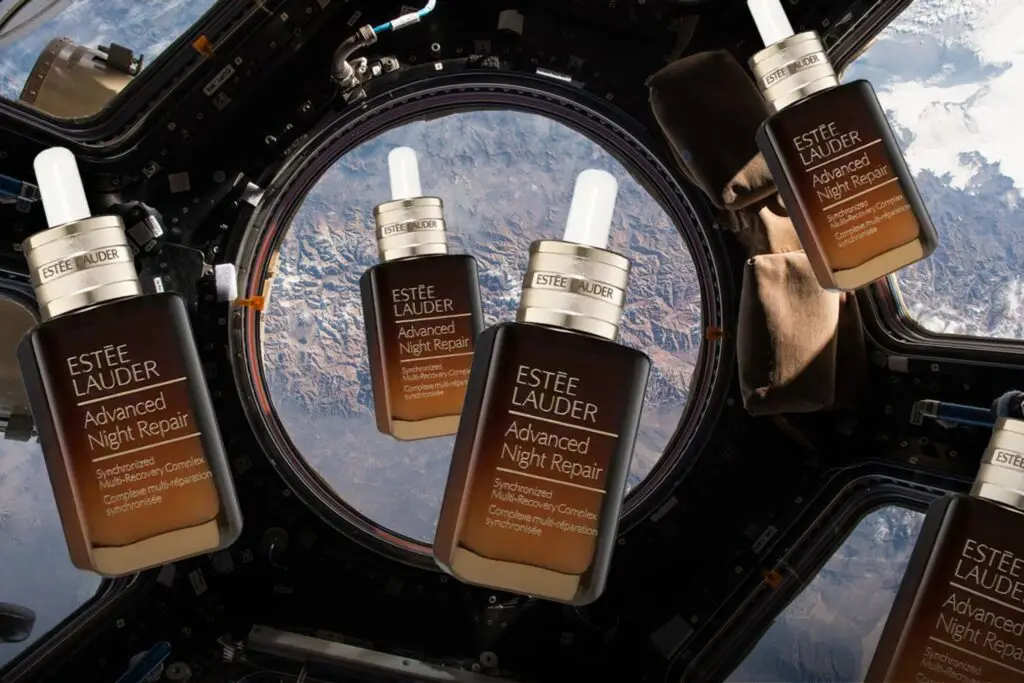 Frascos do sérum Advanced Night Repair da Estée Lauder flutuando na Cupula da ISS com a Terra ao fundo.