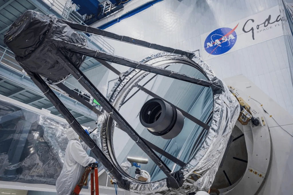Um engenheiro óptico inspeciona o espelho primário do telescópio espacial Roman da NASA logo após ele ter sido retirado do contêiner de transporte.