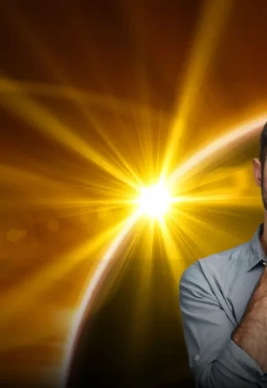 Homem branco barbudo com expressão pensativa vestindo camisa social atrás uma imagem que ilustra eclipses solares e lunares